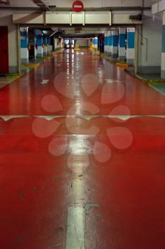 Underground multi-storey car park interior. Red driveway and approaching car.