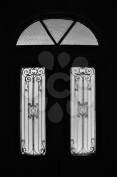 Vintage door frame with decorative motif and arched glass lite. Abandoned neoclassical house dark interior black and white.