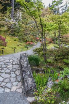 A rock bridge leads to blooming flowers in a Seattle garden.