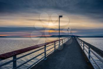 A veiw of the pier in Des Moines, Washington at sunset. The sky is cloudy.