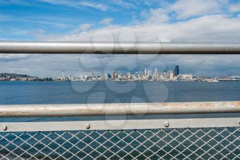 Metal railings frame the Seattle skyloine and part of Queen Anne Hill. Shot taken from Alki Beach.