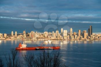 Skyscrapers in Seattle reflect the sun as a ship moves across Elliott Bay.