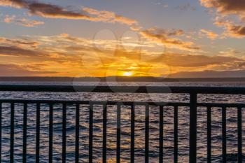 A view of a fence and golden sunset  across the Puget Sound from West Seattle, Washington.