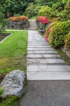 A walkway is in fron of a rock wall with flowers at a seattle garden.