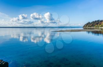 Puffy clouds are reflected in the water of the Puget Sound in Washington State.