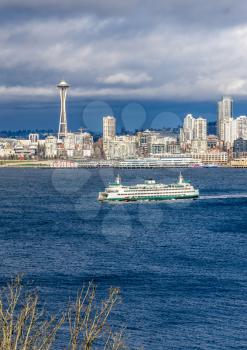 A ferry moves across Elliott Bay in front of skyscrapers in Seattle, Washington.