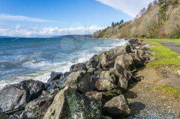 Rocks line the shore at Saltwater State Park in Des Moines, Washington. It is a windy day.