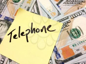 American cash money and yellow sticky note with text Telephone in black color aerial view