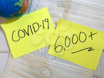 Coronavirus COVID-19 infection medical cases and deaths numbers. China COVID respiratory disease influenza virus statistics hand written on surgical mask and earth globe background