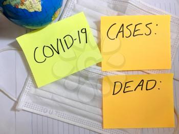 Coronavirus COVID-19 Worldwide infection medical cases and deaths. China COVID respiratory disease influenza virus statistics hand written on surgical mask and earth globe background