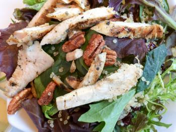 Gourmet walnut mixed greens salad with chicken close up on table