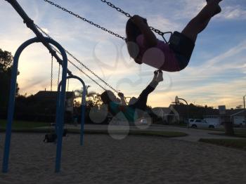 Kids girls on swing and sunset or sunrise
