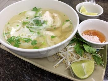 Vietnamese pho chicken noodle soup on tray at restaurant
