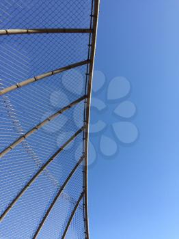 Geometric design element chain link baseball backstop fence and blue sky