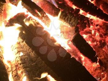 firewood logs burning bonfire pit bright hot flames close up windy beach