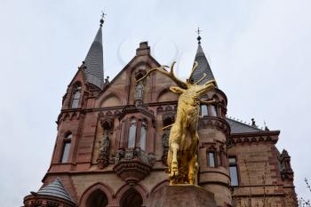 Konigswinter, Germany - 2 March 2019: Drachenburg castle on a gloomy day with a statue of golden deer