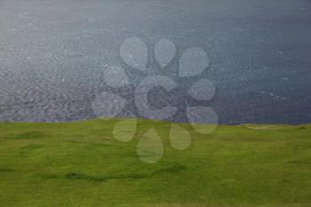 Blue ocean and green grass texture a high contrast minimalist landscape, Faroe Islands
