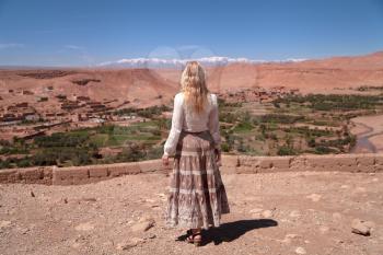 Road trip around Morocco, girl looking at the horizon across red desert, North Africa