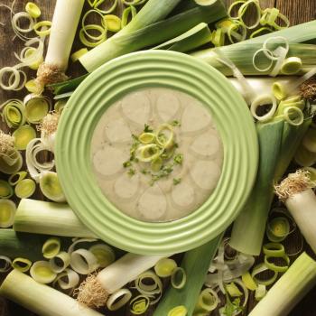 Top view of a bowl of leek soup surrounded by leek rings  and pieces.
