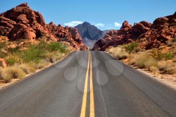 Straigh road into Valley of fire in Nevada with mountains in background