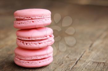 Row of three pink macarons on a wooden table