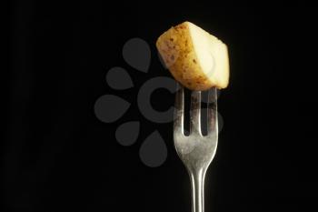 Piece of potato on a fork on a black background