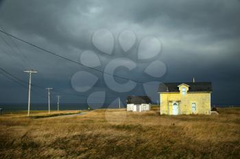 Old fisherman house with yellow tiles in a dark grey sky in iles de la madeleine in Canada