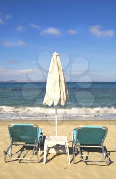 Sunbathing chairs and umbrella on St-Georges beach in Naxos, Greece