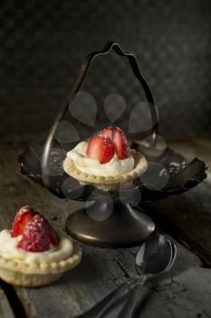 Strawberry tarts with spoon in a stand with rustic style