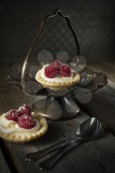 Raspberry tarts with spoons in a stand with a rustic style
