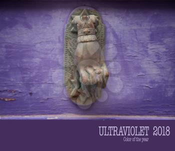 Hand as a handle door on a grunge violet wall of an old house.   Color of the year, ultraviolet.