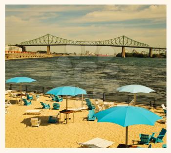 Turquoise umbrella on a urban beach in front of Jacques Cartier Bridge, downtown Montreal, Canada.  Retro effects to look like an aged instant pictures.