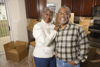 Royalty Free Photo of an Older Couple Standing in a Kitchen Full of Moving Boxes