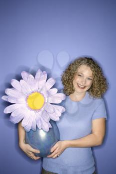 Royalty Free Photo of a Woman Holding a Flower Pot with a Over Sized Fake Flower