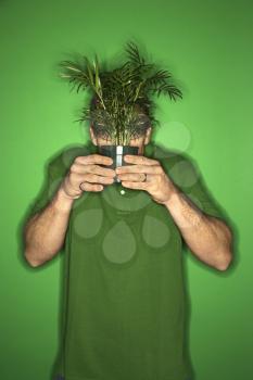 Royalty Free Photo of a Portrait Man Holding a Plant in Front of His Face