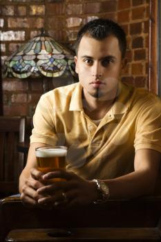 Royalty Free Photo of a Serious Man Holding a Beer in a Pub