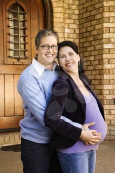 Royalty Free Photo of a Pregnant Woman and Husband Standing in a Doorway
