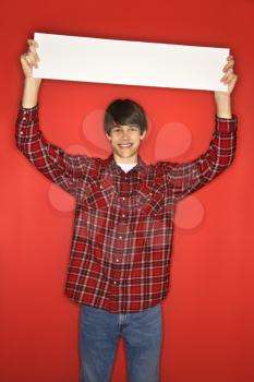 Royalty Free Photo of a Teen Boy Holding a Blank Sign Above His Head
