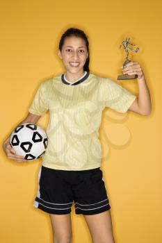Royalty Free Photo of a Teen Girl Holding a Soccer Ball and Trophy