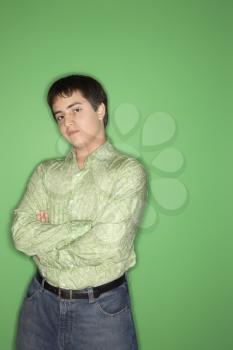 Royalty Free Photo of a Teen Boy With Crossed Arms Standing Against a Green Background