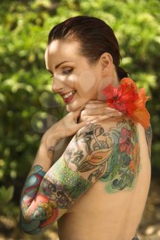 Royalty Free Photo of a Smiling Tattooed Woman with Hibiscus Flower Over Her Shoulder in Maui, Hawaii, USA