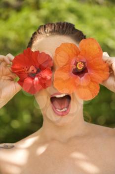 Royalty Free Photo of a Topless Woman Holding Hibiscus Flowers Over Her Eyes With Mouth Open in Maui, Hawaii, USA