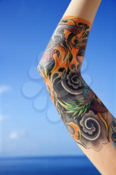 Royalty Free Photo of a Tattooed Woman's Arm With the Pacific Ocean in Background in Maui, Hawaii, USA