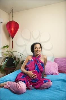 Royalty Free Photo of a Pregnant Woman With Her Hands on Stomach in a Bedroom