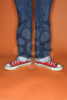 Royalty Free Photo of a Person in Jeans and Sneakers With Feet Turned Outward
