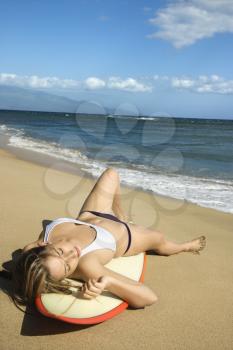 Royalty Free Photo of a Woman in a Bikini Lying on a Surfboard Sunbathing at a Beach in Maui Hawaii