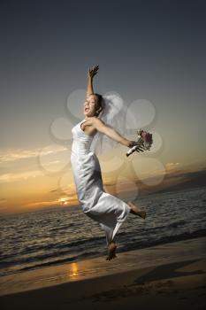 Royalty Free Photo of a Bride Jumping on the Beach