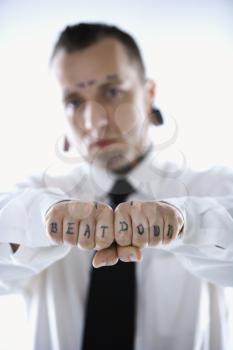 Royalty Free Photo of a Man With Tattoos and Piercings Holding Out His Fists Reading Beat Down