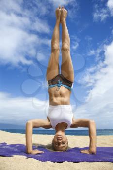 Royalty Free Photo of a Caucasian Woman Doing Yoga on the Beach