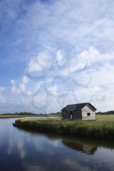 Royalty Free Photo of a Weathered Building in a Marsh on a Creek